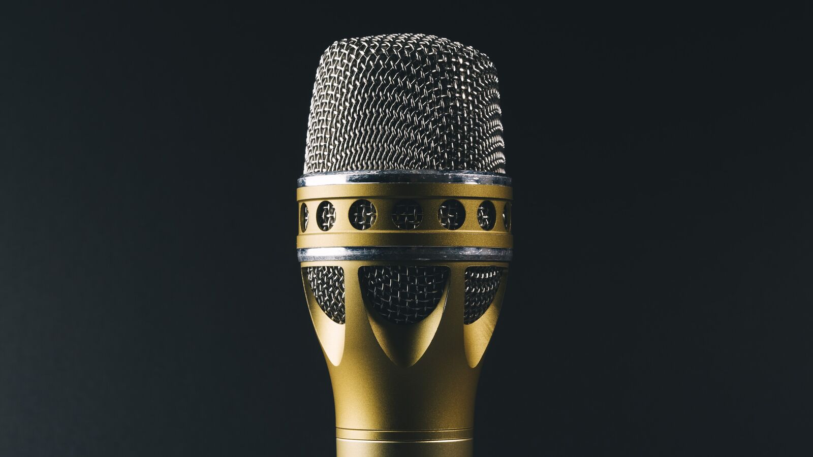 A dynamic microphone with a gold and silver grille against a dark background