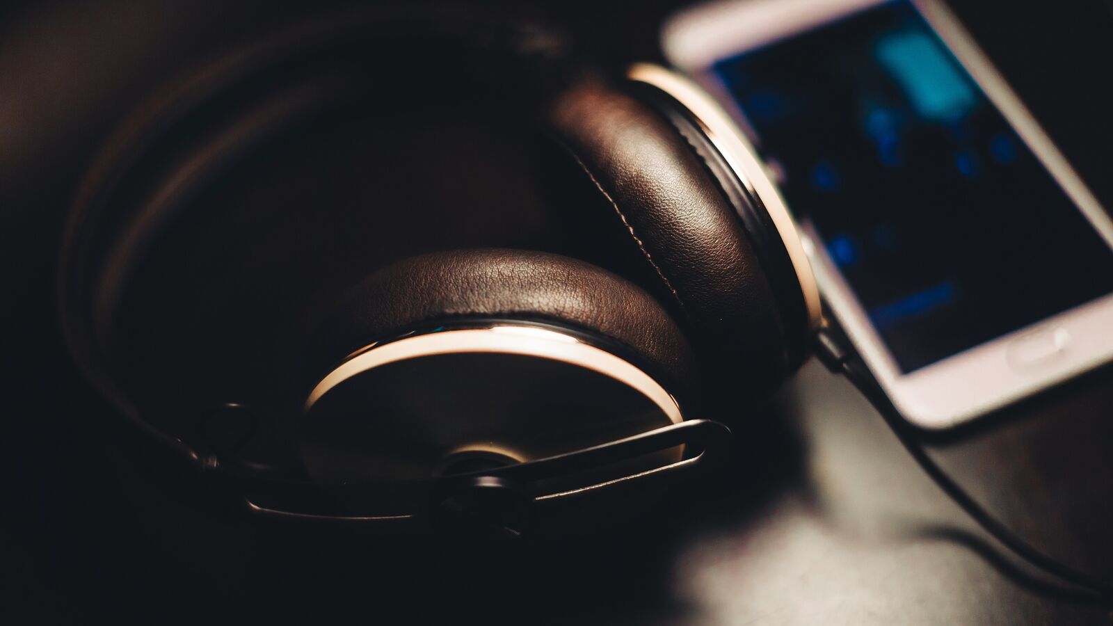 Black over-ear headphones lying next to a smartphone in dim light
