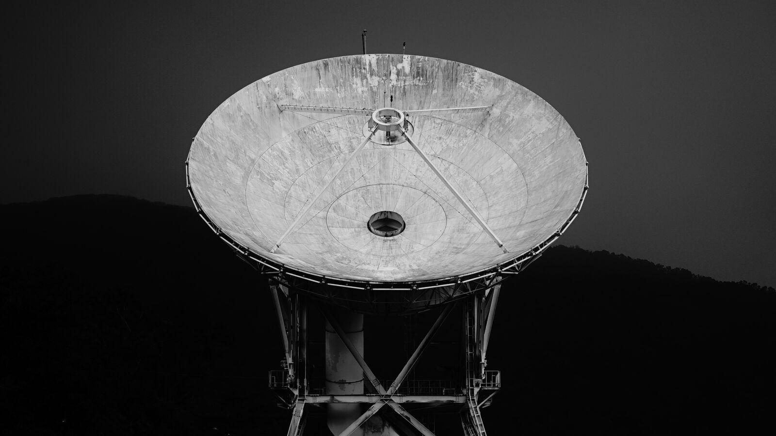 Eine Satellitenschüssel zeigt nach oben vor grauem Himmel